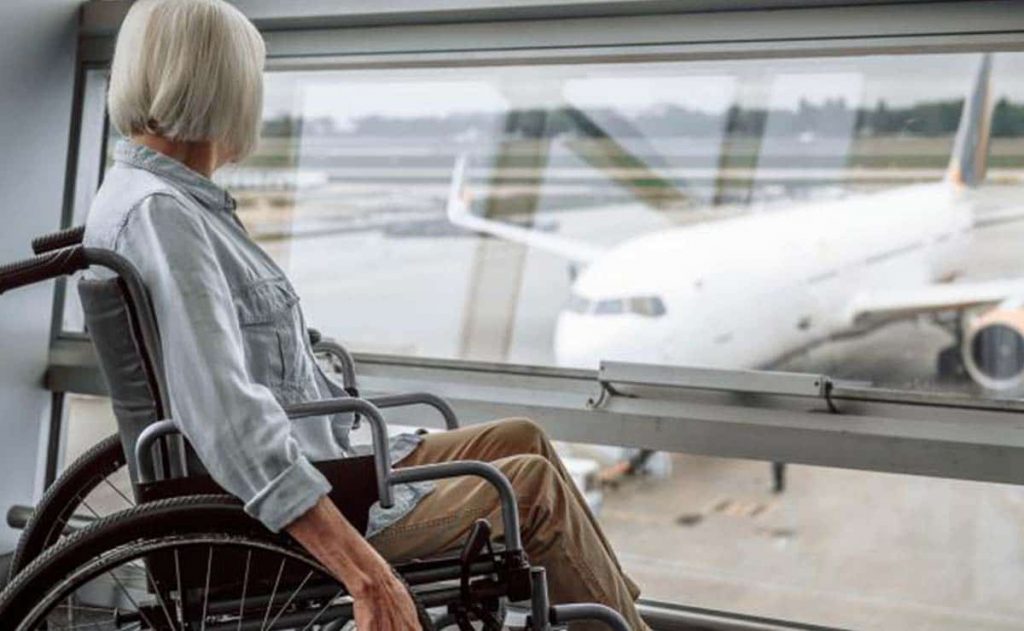 Una mujer en silla de ruedas mirando un avión antes de embarcar
